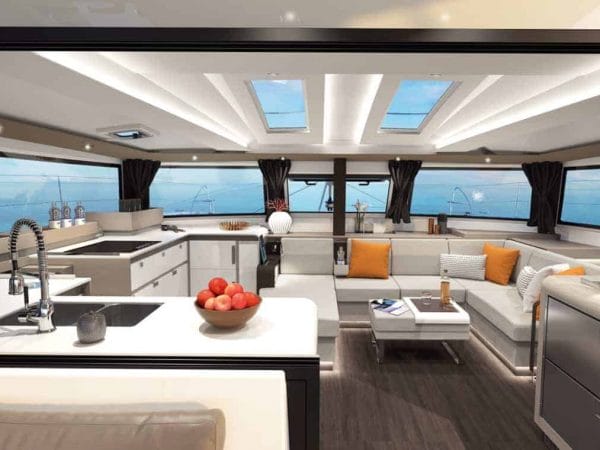 Overview of the stylish interior of the galley and saloon of the spacious Fountaine Pajot New 45 with modern design and orange pillows